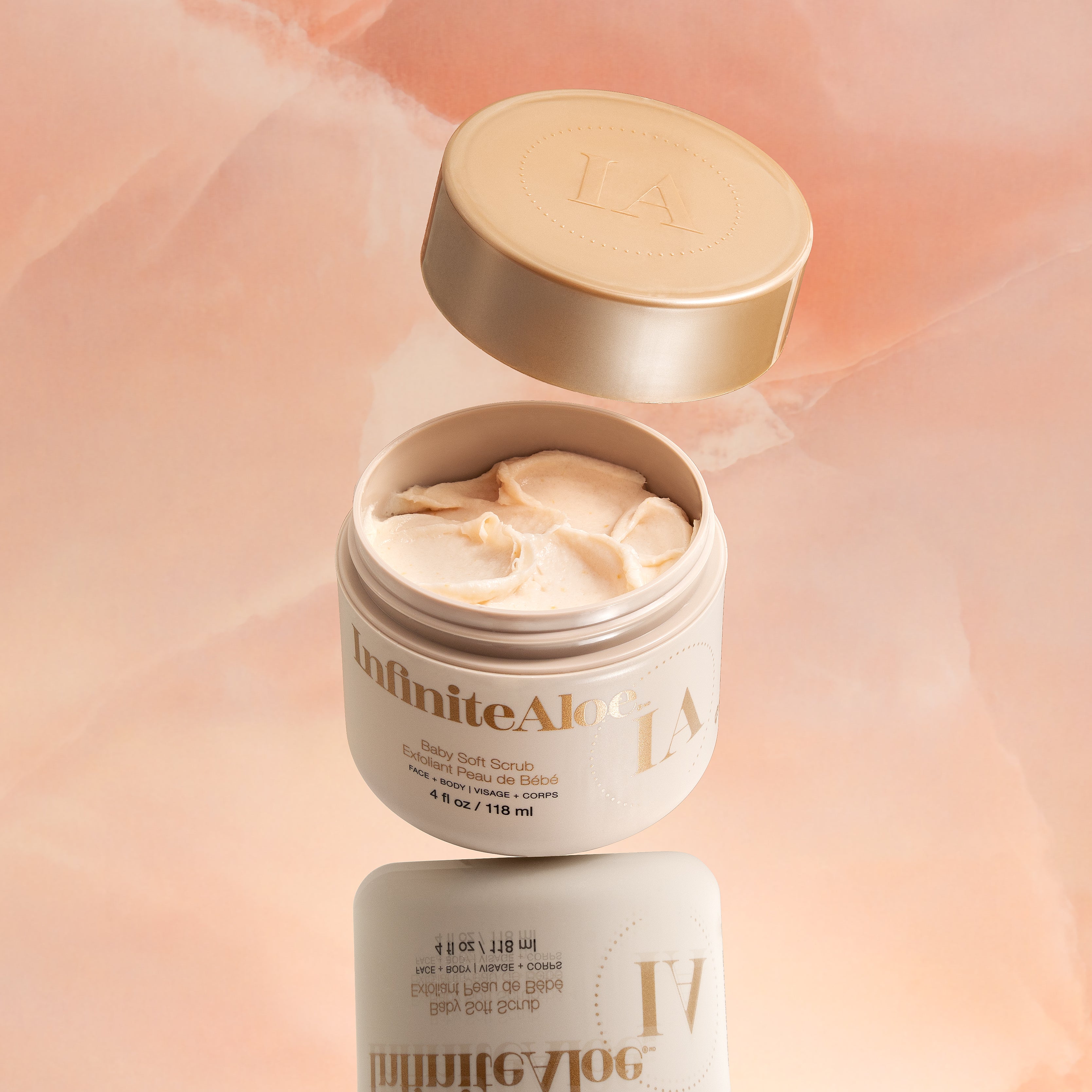 InfiniteAloe body scrub jar with open lid on a soft pink background